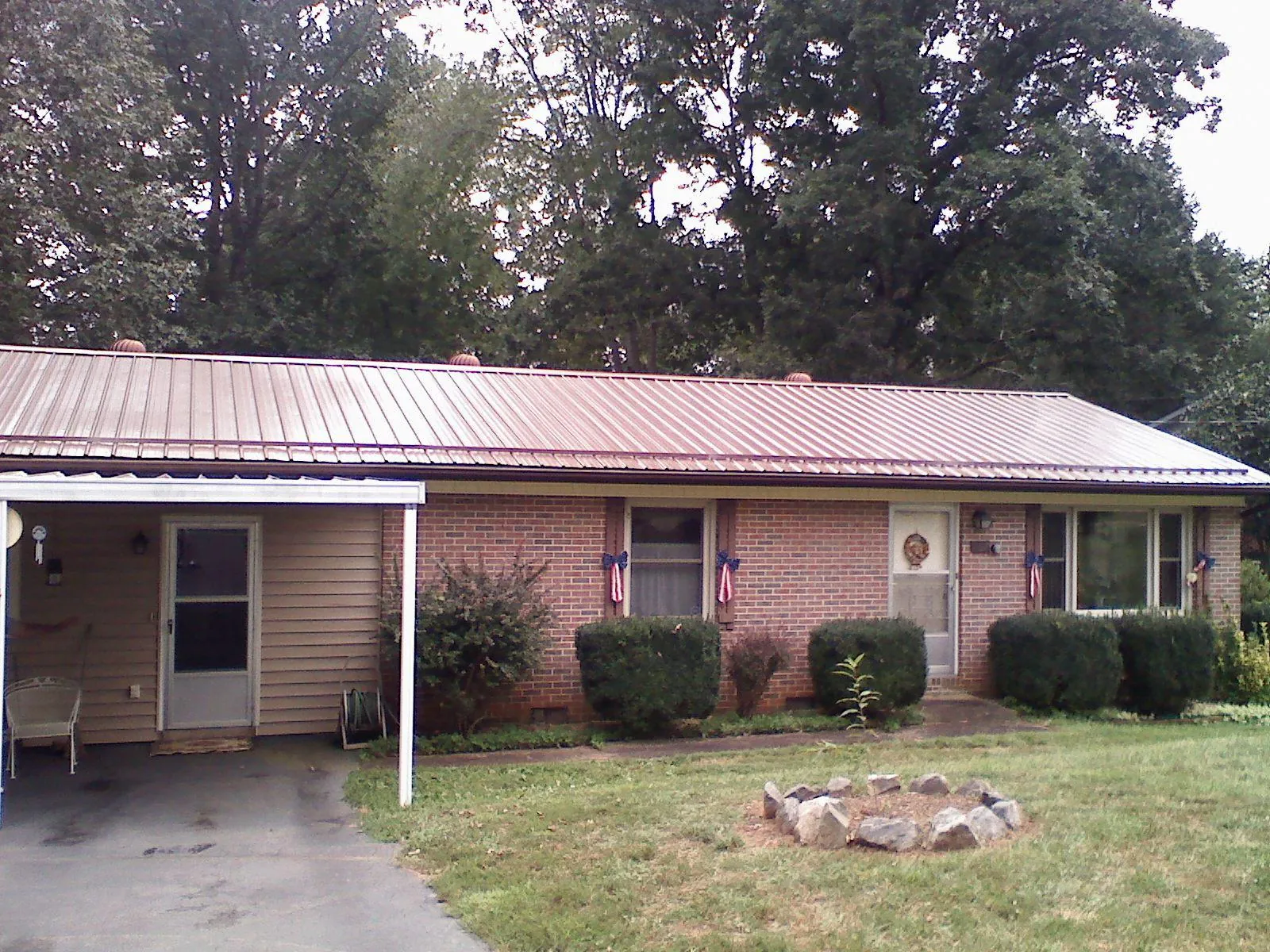 Bronze metal roof and carport on a brick ranch home — Roof Repair work by our crew in Emporia