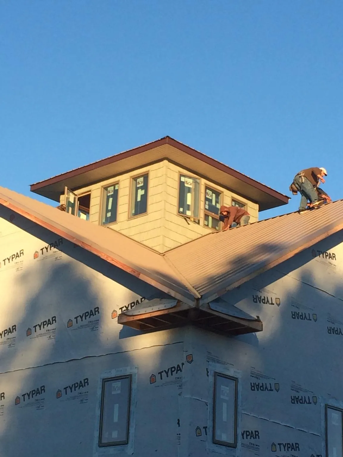 Roofers working around a rooftop cupola on a new metal roof at sunset — Roof Waterproofing in Emporia by Roofing Brothers